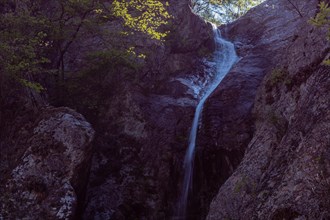 Water cascades down a rocky surface amid twilight hues, in South Korea