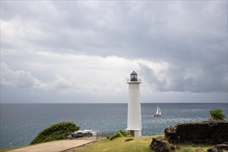 White lighthouse on a steep coast. Dramatic clouds with a view of the sea, pure Caribbean at Le