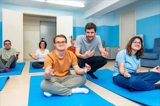 Friendly male yoga instructor directing a class with people with special needs and down syndrome