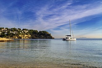 Yacht anchored near the beach with coastal homes under a sunset sky, Coastal Hiking tour in the