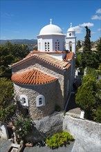 View of a church with a white dome and terracotta roofs against a clear blue sky, Holy Monastery of