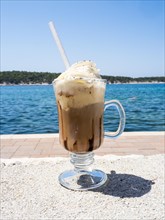 Iced coffee with whipped cream, the sea in the background, Rab Island, Kvarner Gulf Bay, Croatia,