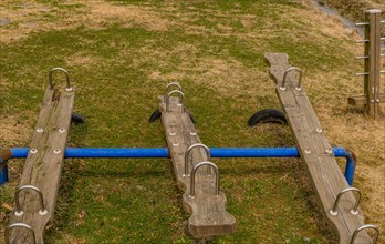 Wooden seesaw playground equipment on a well-maintained grassy field, in South Korea