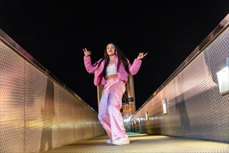 Low angle view photo of a happy trap dancer in pink clothes dancing alone outdoors at night