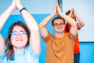 Happy group of disabled people raising arms practicing yoga in the gym