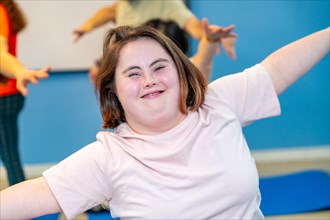 Woman with down syndrome smiling at camera while exercising in the gym