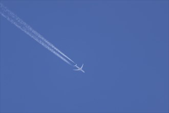 Jet aircraft in flight with a contrail or vapour trail behind in the sky, England, United Kingdom,