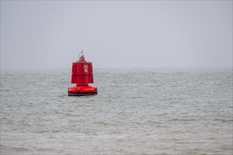 A red buoy floats in front of the calm waters of the sea