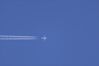 Boeing 737 jet aircraft in flight with a contrail or vapour trail behind in the sky, England,