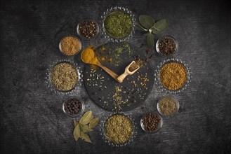 Spice clock, circular arrangement of various spices on a dark background