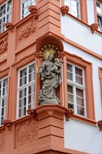 Baroque statue on a terracotta-coloured house facade with golden rays, Heidelberg,