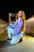 Vertical portrait of a caucasian blonde woman with urban hip hop style outdoors at night