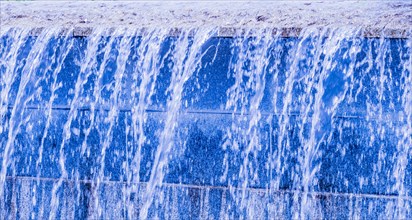 Blue-hued man-made waterfall streaming down a wall, in South Korea