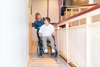 Kind nurse and disabled man with down syndrome talking while using wheelchair