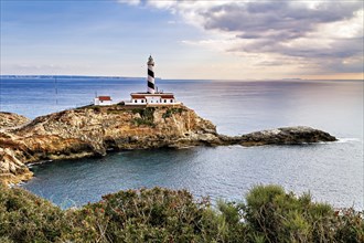 Lighthouse standing on rocky cliffs surrounded by calm sea waters at dusk, Coastal Hiking tour in
