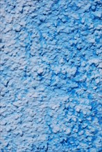 Close-up of a blue textured wall with peeling paint and crackled surface