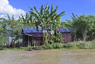 Colourful wooden houses on a quiet riverbank surrounded by lush vegetation, Inle Lake, Myanmar,
