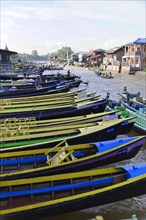 Row of colourful boats on a river bank with houses in the background, Pindaya, Inle Lake, Myanmar,