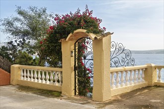 Mediterranean style gate with blooming flowers and ocean view, Peguera, Mallorca