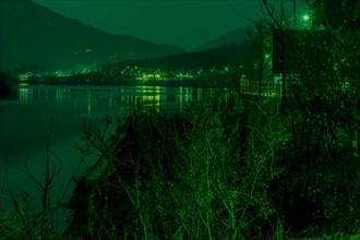 Serene green-tinged night view of a lake with mountains in the background, in South Korea