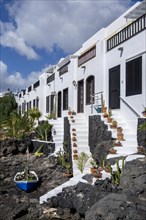 Typical white houses with small gardens on lava rock, on the promenade of Puerto del Carmen,