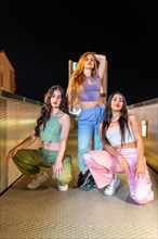 Vertical portrait of three beauty hip hop dancers posing together in the city at night