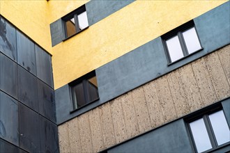 Corner view of a building with yellow wall, grey levels and black details