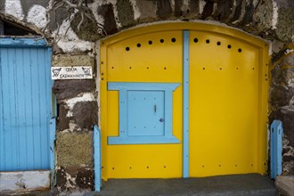 Yellow garage door in stone wall, climate, Milos, Cyclades, Greece, Europe