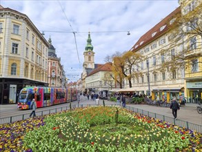 Graz, Austria, 26.03.2023: Colorful spring flowers in Jakominiplatz Square and Parish Church in the