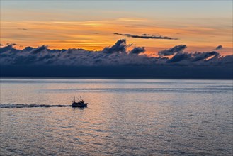 A lone boat on the ocean at sunset under a cloudy sky, Lofoten