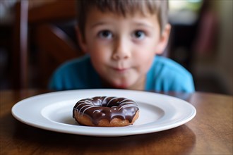 Plate with donut on table with child in blurry background. Concept for unhealthy eating habbits