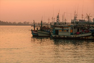 Moored fishing boats bask in the warm glow of the sunset in Koh Sdach Island in Cambodia