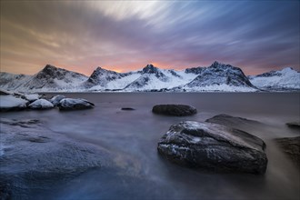 Rocky coast at the fjord with snow-covered mountains at sunset, Steinfjorden, Tungeneset,
