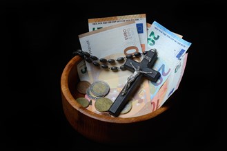 Crucifix and banknotes in a bowl, church and money, church tax