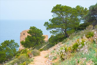 Ruin of an old watchtower in front of a Mediterranean coastal landscape with surrounding nature,