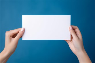 Female hands holding up empty white note in front of blue background. KI generiert, generiert AI