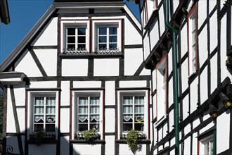 Detailed view of a half-timbered facade with flower-decorated windows and sunlight, old town