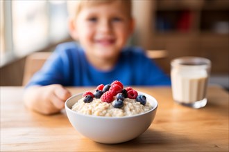 Table with bowl with healthy breakfast oatmeal porridge with berry fruits and happy smiling young