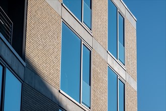 Window and facade of a brick building with shadows and clear sky