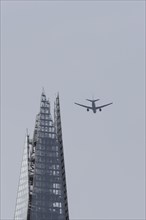 Airbus aircraft in flight over The Shard city skyscraper building, London, England, United Kingdom,