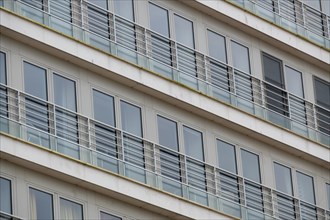 Symmetrical view of residential balconies with glass railings and white frames, Blankenberge,
