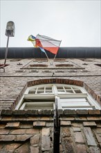 Polish and Ukrainian flag waving together on brick house in Katowice Nikiszowiec, southern Poland