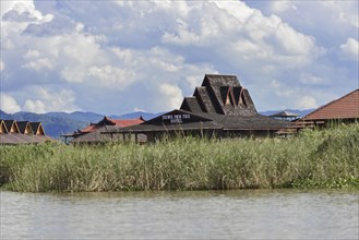 View of a resort with pointed roofs on the banks of a river, Inle Lake, Myanmar, Asia