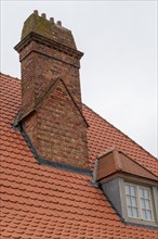 Traditional red brick chimney on a roof with small windows, DeHaan, Flanders, Belgium, Europe