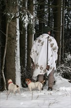 Hunter in winter with snow shirt and hunting dogs Jack Russell Terrier, Allgaeu, Bavaria, Germany,