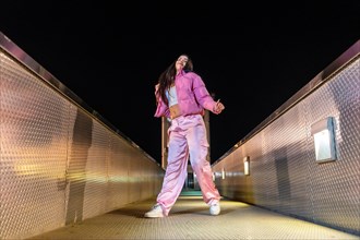 Low angle view photo of a young artist dancing hip hop on a bridge at night