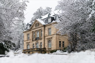 Large villa in winter, surrounded by snow-covered trees under a cloudy sky, Briller Viertel,