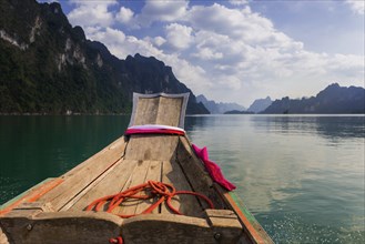 Traditional longtail boat in front of limestone rocks in Cheow Lan Lake in Khao Sok National Park,