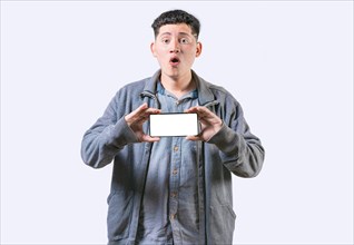 Surprised guy showing cell phone screen isolated. Amazed young man showing an advertisement on
