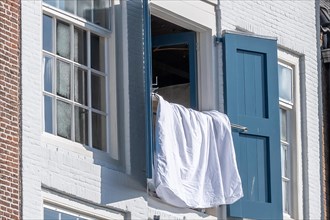 Close-up of an open window with blue shutters and a white shirt, Middelburg, Zeeland, Netherlands